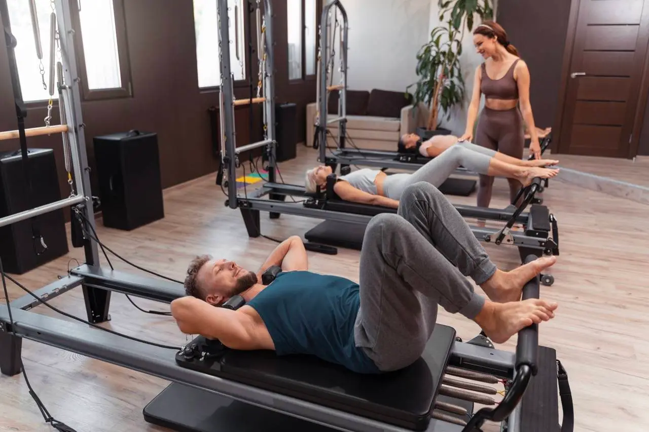 Ομαδικό μάθημα Reformer Pilates με άντρα και γυναίκες στις μηχανές