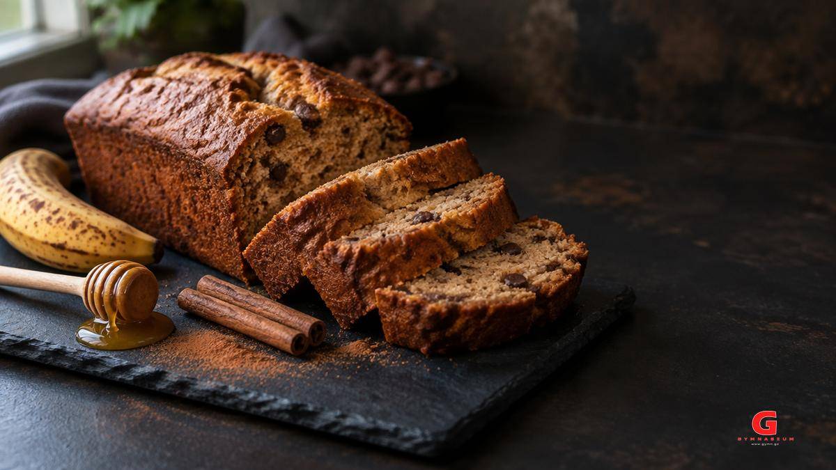 Σπιτικό banana bread σε φέτες πάνω σε πλάκα με μπανάνα, μέλι και ξυλάκια κανέλας