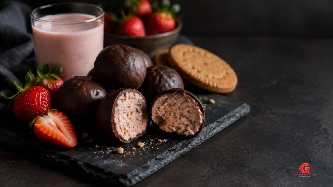 Energy balls με επικάλυψη σοκολάτας, κομμένες στη μέση, με φράουλες και ποτήρι κεφίρ φράουλα