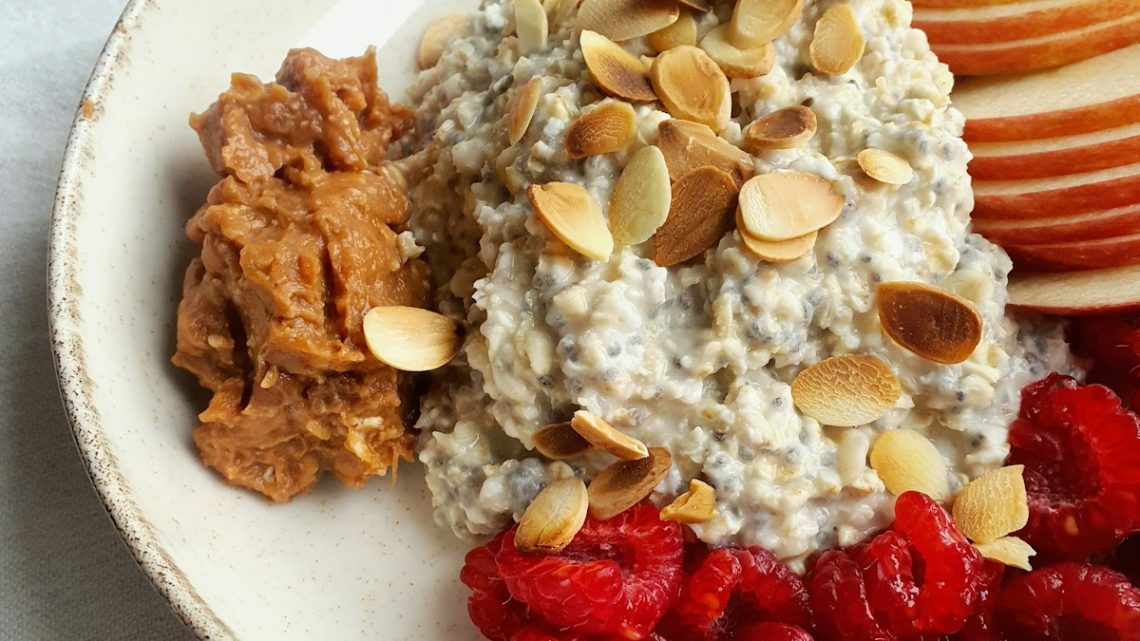 Πιάτο με oatmeal, φυστικοβούτυρο, φέτες μήλου, φιλέ αμυγδάλου και σμέουρα