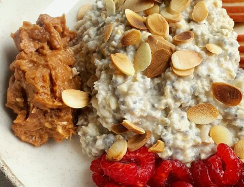 Πιάτο με oatmeal, φυστικοβούτυρο, φέτες μήλου, φιλέ αμυγδάλου και σμέουρα