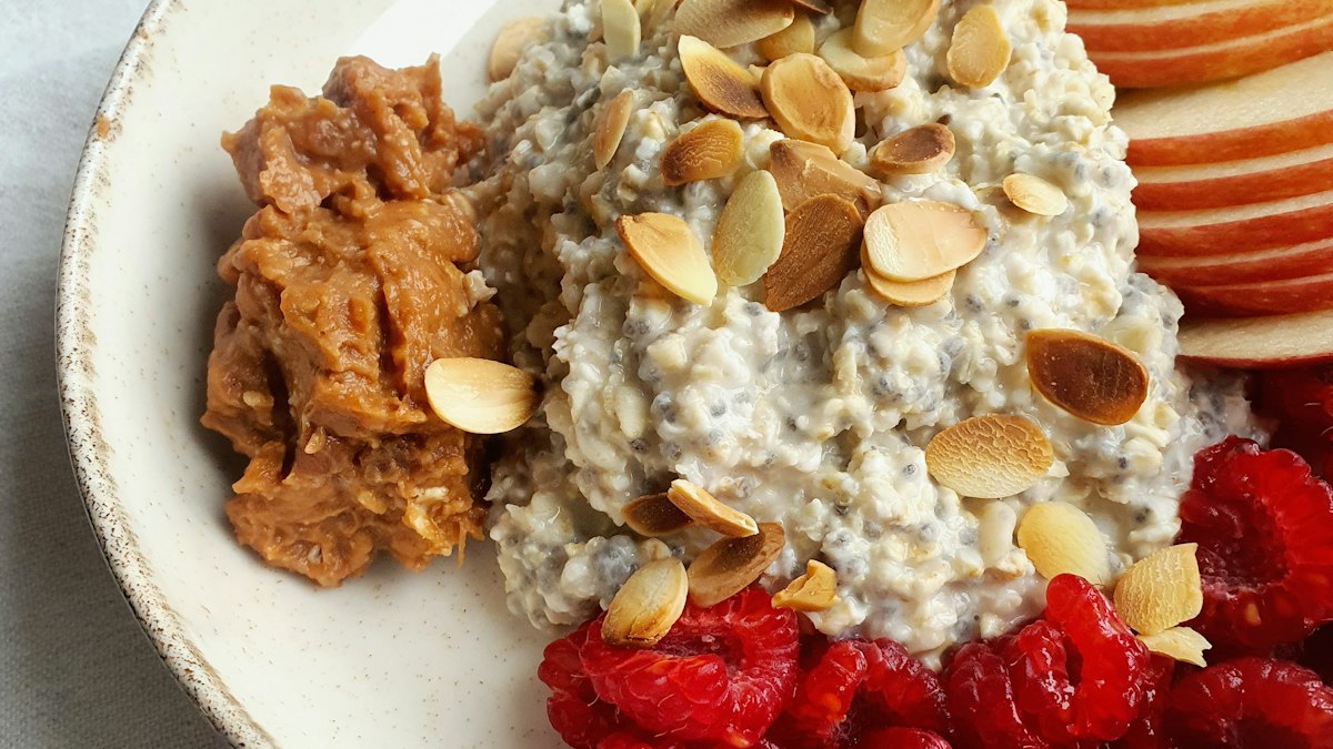 Πιάτο με oatmeal, φυστικοβούτυρο, φέτες μήλου, φιλέ αμυγδάλου και σμέουρα