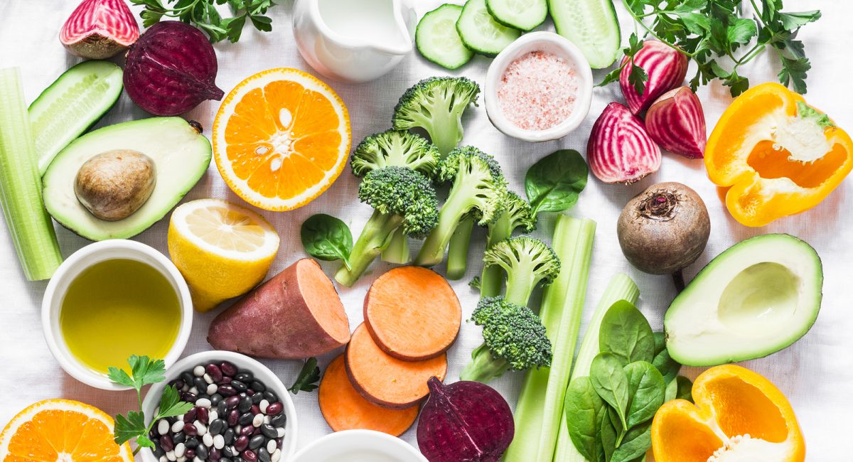 Five best vitamins for beautiful skin. Products with vitamins A, B, C, E, K - broccoli, sweet potatoes, orange, avocado, spinach, peppers, olive oil, dairy, beets, cucumber, beens. Flat lay, top view